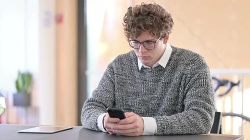 Young Adult Using Smartphone at Desk Indoors