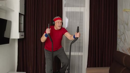 Active Senior Man Exercising on Elliptical Machine at Home