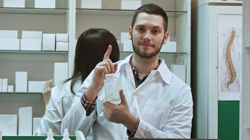 Pharmacist Holding Medication Bottle in Pharmacy Setting
