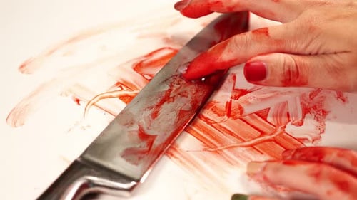 Person Hand Runs Fingers on Silver Knife with Blood Closeup