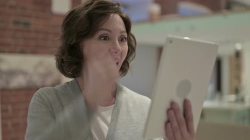 Excited Woman Reacting to Tablet Content Indoors