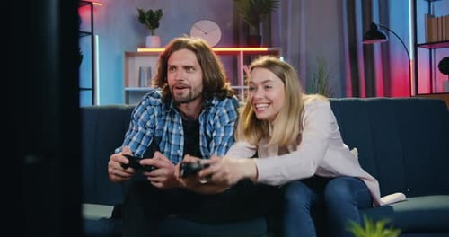 Couple Competitively Playing Video Games at Home