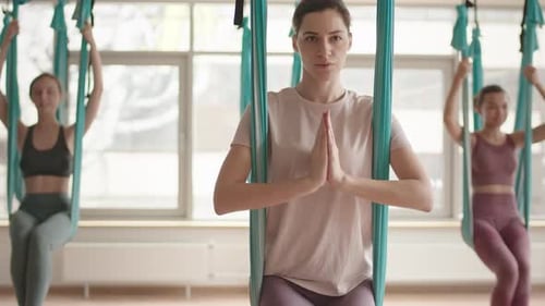 Women Practice Aerial Yoga in Hammocks Indoors