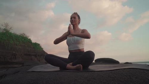 Woman Meditating on Beach at Sunrise