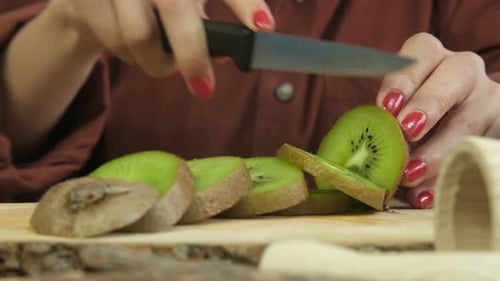 Woman Slicing a Kiwi With a Knife