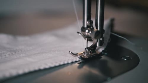 Close-up of Sewing Machine Needle with Thread Pierces Fabric in Slow Motion