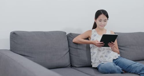 Woman Using Tablet Relaxing on Gray Couch