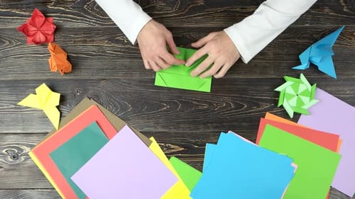 Mann faltet Origami aus grünem Papier.