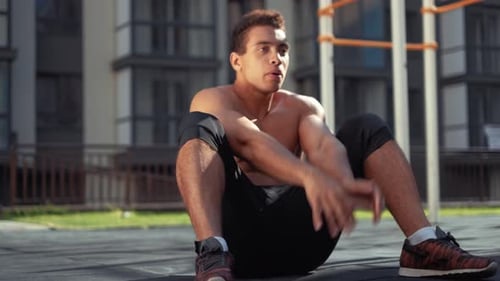 Close Up Portrait of a Young Man Doing Sit Ups. Outdoor Gym