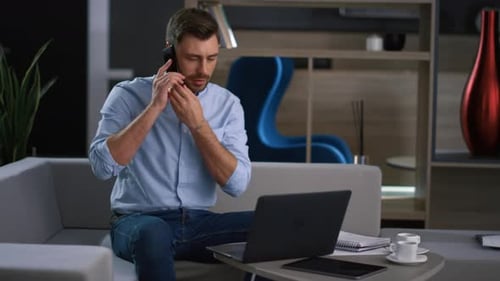 Businessman Calling Mobile Phone Managing Corporate Finance on Laptop in Office