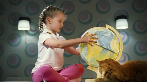 Girl Spinning Globe with Her Cat Inside Home