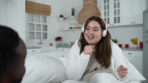 Woman Singing with Headphones in Cozy Bedroom