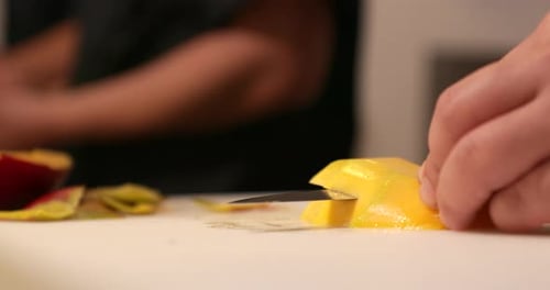 Chef Slicing Ripe Mango Horizontally Using Sharp Knife At The Kitchen. - Close Up Shot