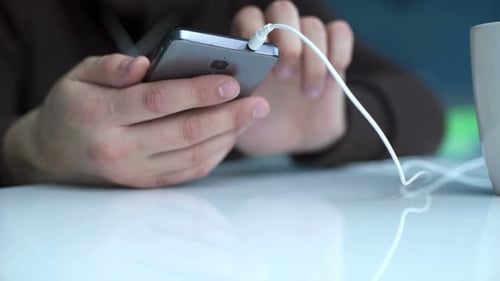 Man Using Smartphone Charging on White Table