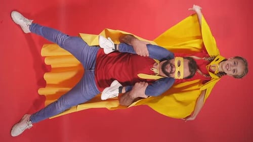 Father and Daughter Superheroes Play on Red Background