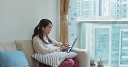 Woman Using Laptop on Couch in Urban Apartment