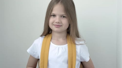 Portrait of Pretty Cute Smiling School Girl in White Tshort with Yellow Backpack on Gray Background
