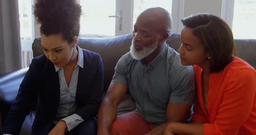 Mixed race female real estate agent discussing over property with mature couple at home 4k