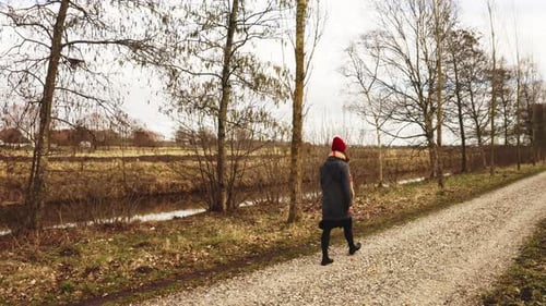 Woman Walking on Rural Path Near Stream
