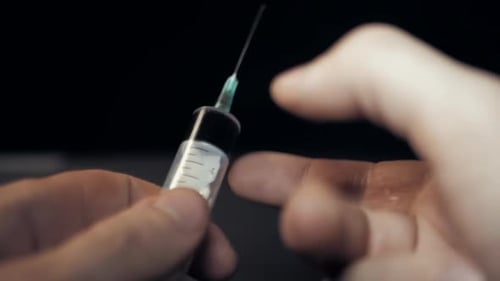 Close Up of Hands Holding a Syringe