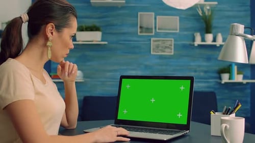 Young Adult Woman Looking at Green Screen Laptop