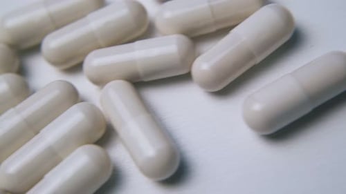 Pile of White Capsules and Yellow Pills