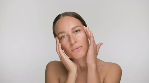 Close-up Beauty Portrait of Young Woman with Smooth Healthy Skin, She Gently Touches Her Face with