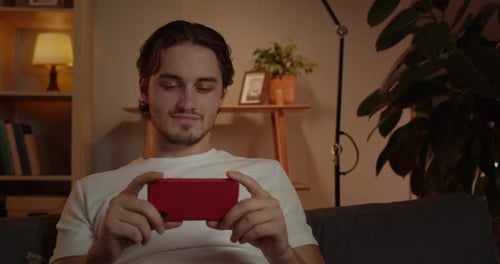 Crop View of Young Man Watching Video While Sitting on Sofa at Home
