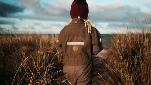 Girl Walking Through Grass To The Sea