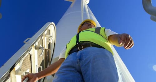 Male engineer standing on a wind mill in the wind farm 4k