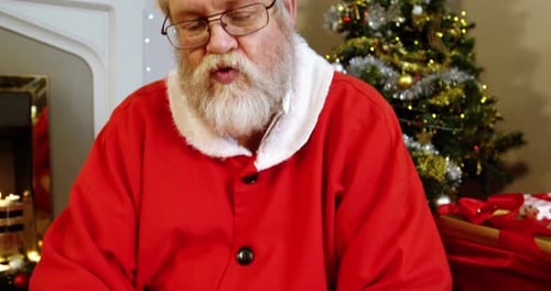 Santa Claus Sitting by Christmas Tree and Fireplace