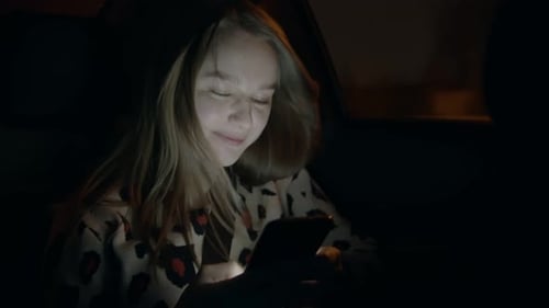 Smiling Woman Using Smartphone in Car at Night