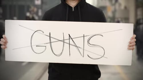 Unbekannter Randalierer hält ein Plakat mit NO GUNS Text