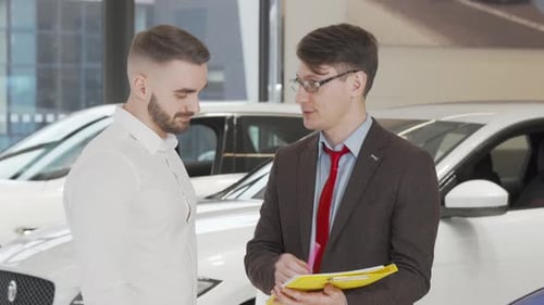 Handsome Man Signing Papers at Dealership After Buying New Automobile