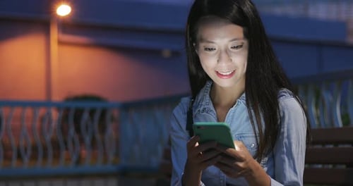 Woman Smiling Using Mobile Phone at Night