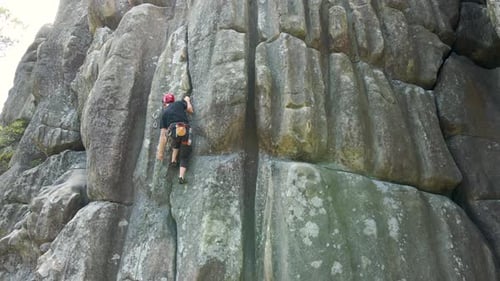 Determined Climber Clambering Up Steep Wall of Rocky Mountain