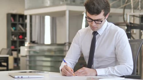 Young Adult Writing at Desk in Modern Office
