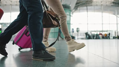Close Up of Travellers Legs with Suitcases Walking at Airport Terminal Tracking Shot Slow Motion