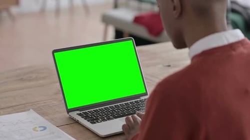 Rear View of African Man Working on Laptop with Green Chroma Screen
