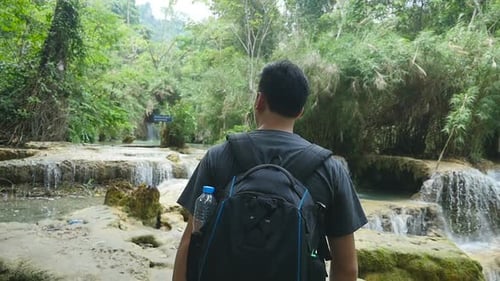 Young Adult Exploring Tropical Waterfalls in Green Forest