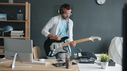 Young Adult Plays Electric Guitar in Office