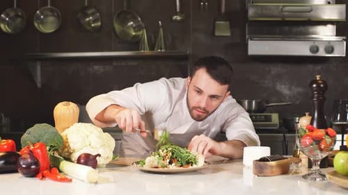Young Chef Decorates His Special Dish with Some Greens. He Works in a Modern Kitchen