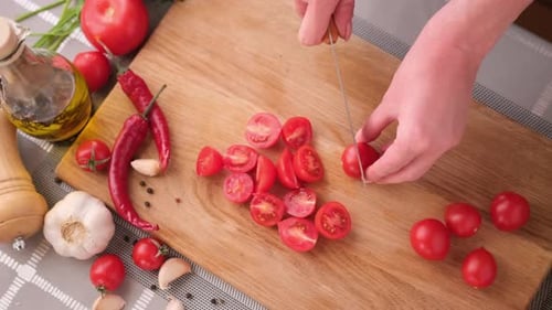 Woman Cutting Fresh Cherry Tomatoes with Kitchen Knife on Wooden Cutting Board