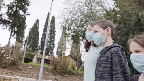 Coronavirus pandemic - kids walking outdoors with face masks to avoid contagion