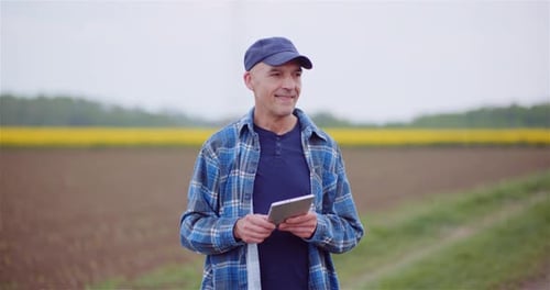 Farmer Examining Agricultural Field While Working on Digital Tablet Computer at Farm