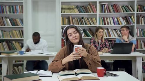 Frau mit langen Haaren im Kopfhörer hört Musik in der Bibliothek