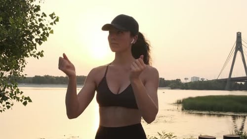 Adult Woman Exercises by River at Sunset
