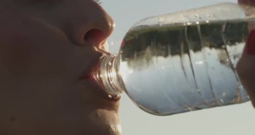 Woman Drinks Water after Exercising Outdoors