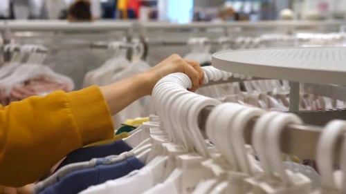 Female Hand Rotating Clothes Rack To Choose an T-shirt. Shopping Concept