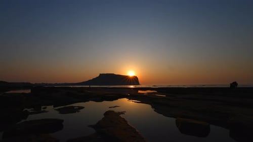 Sonnenaufgang am Strand. die Sonne geht von einer bergähnlichen Insel auf. Silhouette ist wunderschön.